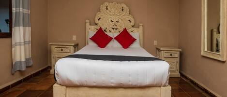 A bedroom with a large bed, two nightstands, a decorative headboard, and a mirror on the wall.