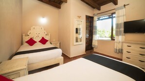 Een slaapkamer met een groot bed, een houten hoofdbord, een nachtkastje, een dressoir, een spiegel en een televisie aan de muur.