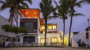 Ein modernes Hotel mit mehrstöckiger Bauweise, Außenbereich mit Sitzgelegenheiten und Palmen.