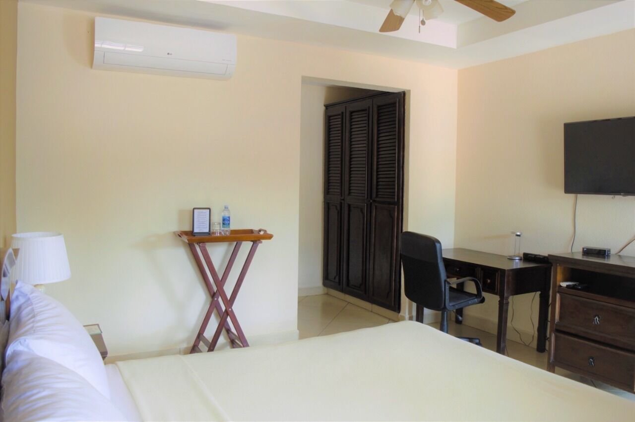 A hotel room with a bed, desk, chair, TV, and wardrobe.