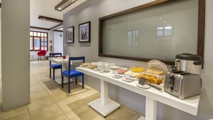A breakfast buffet setup with a variety of food items, a toaster, and a coffee maker on a white table.