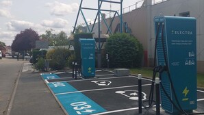 En hotellskylt, en laddstation för elfordon och anvisade parkeringsplatser.