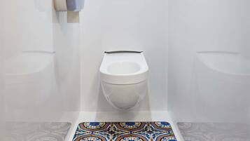 Un baño con inodoro, bidé y suelo estampado.