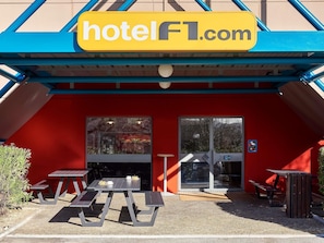 A hotel entrance with a red facade, a glass door, and a sign reading 'hotelFL.com'. - hotelF1 Nantes EST La Beaujoire  (Nantes)