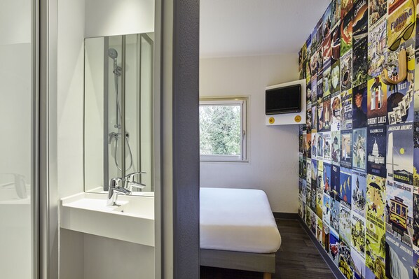 A bathroom with a glass-enclosed shower, a white sink, and a bench. - hotelF1 Nantes EST La Beaujoire  (Nantes)