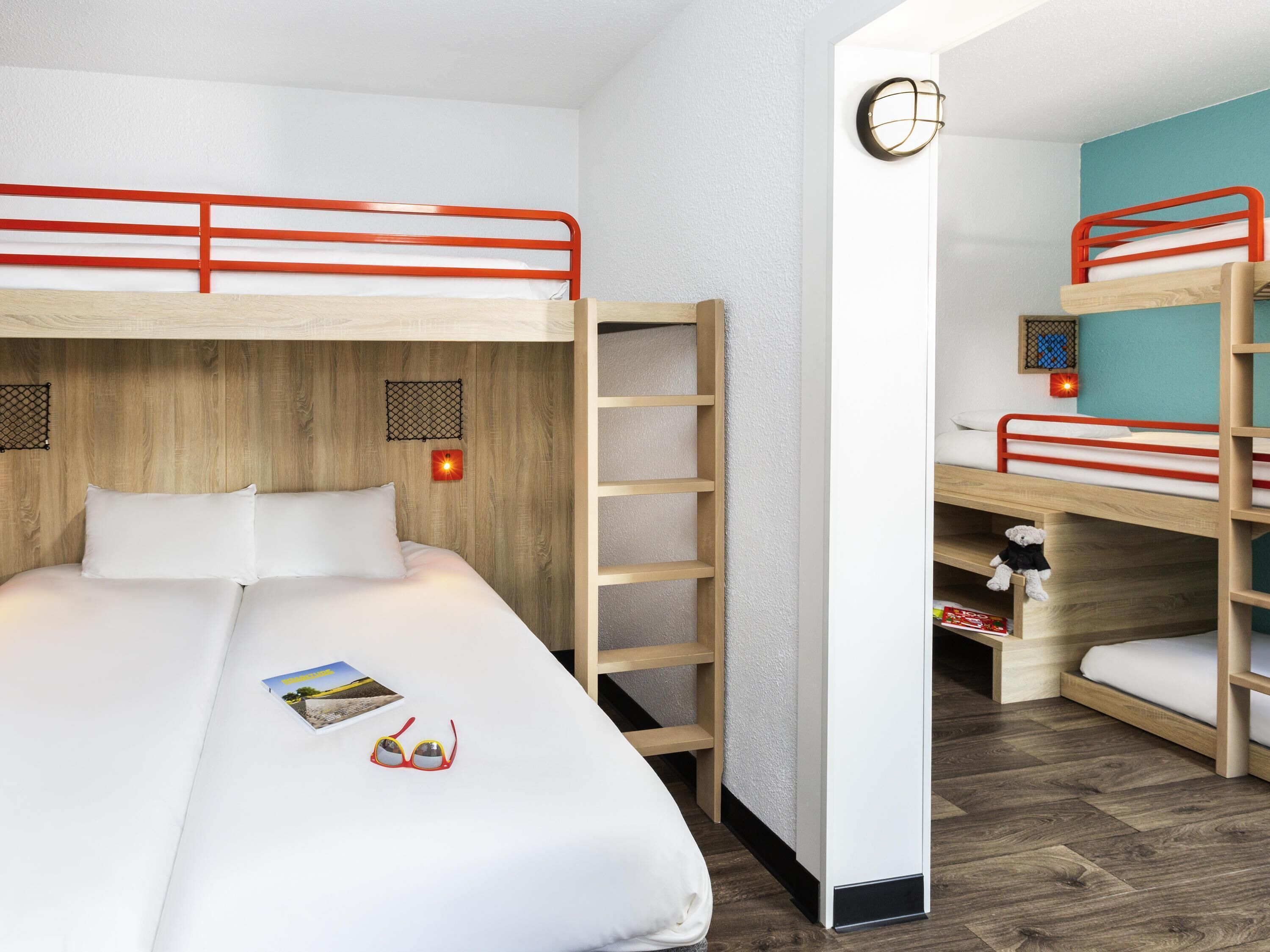 Une chambre avec un lit superposé, une tête de lit en bois, une échelle et une petite étagère sur laquelle est posé un ours en peluche.