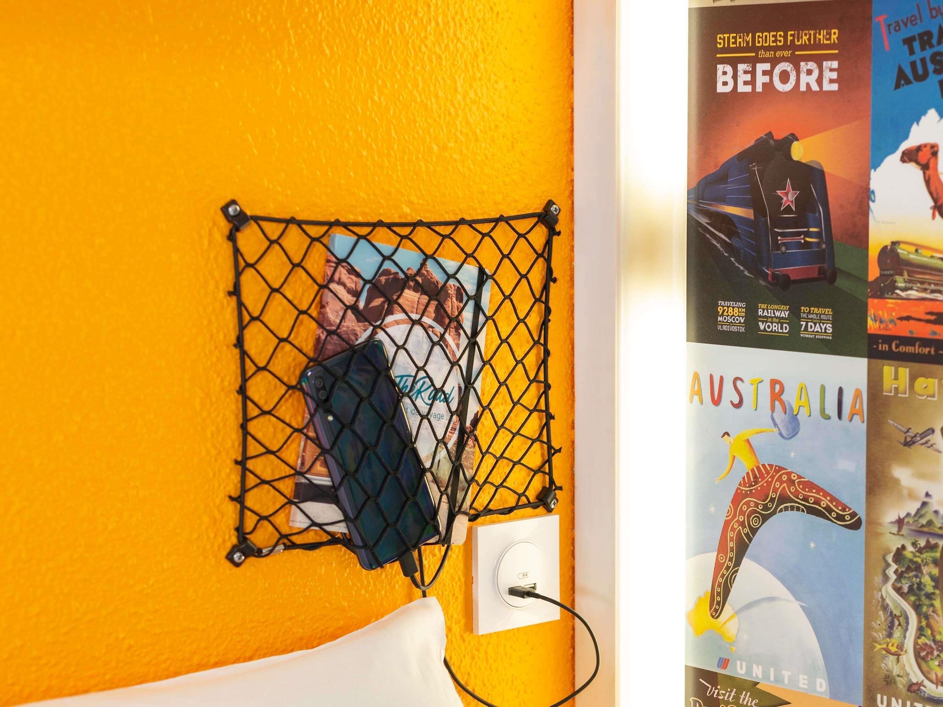 Pared de color amarillo, un enchufe y un cartel que anuncia viajes a Australia.