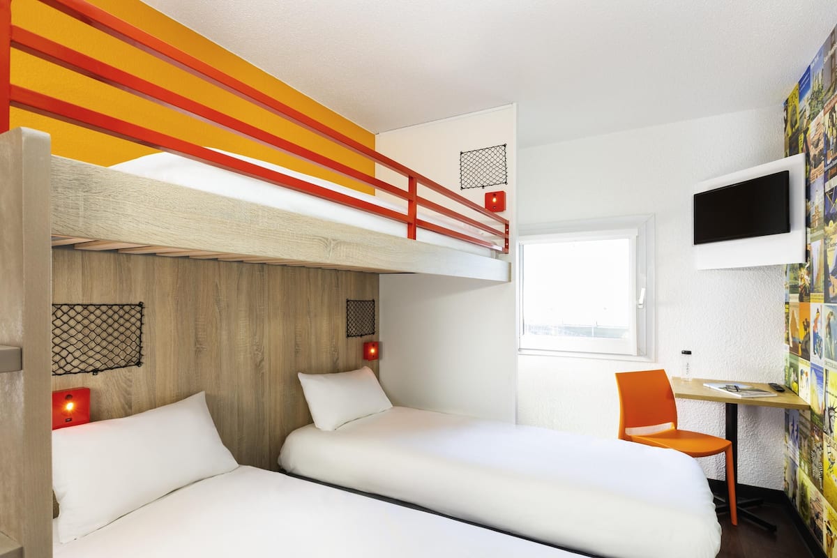 A room with bunk beds, a desk, a chair, and a TV.