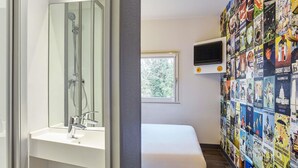 Un baño con ducha, lavabo, inodoro, una ventana y una pared decorada con carteles de viajes.