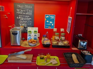 Una mesa de desayuno con un menú en pizarra, un tostador y diferentes alimentos.