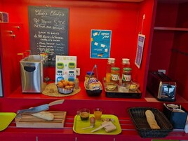 Una mesa de desayuno con un menú en pizarra, un tostador y diferentes alimentos.