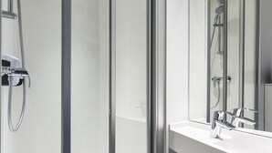 Une salle de bain moderne avec une douche à parois de verre, un lavabo blanc et un grand miroir.