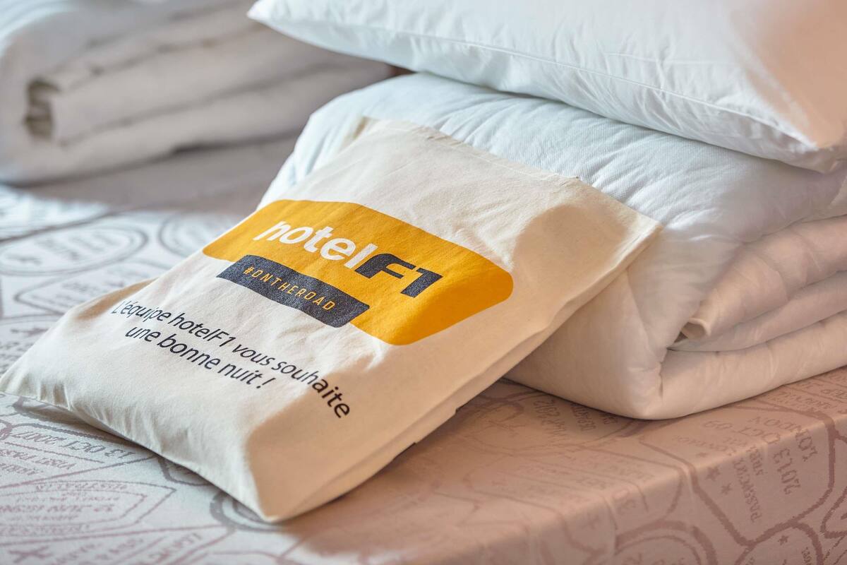 A neatly made bed with pillows and a folded blanket.