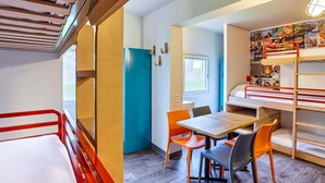 Una habitación pequeña con literas, una mesita y sillas.