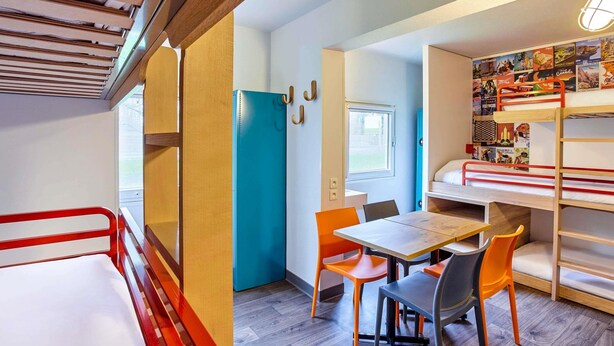 Une petite pièce avec des lits superposés, une petite table et des chaises.