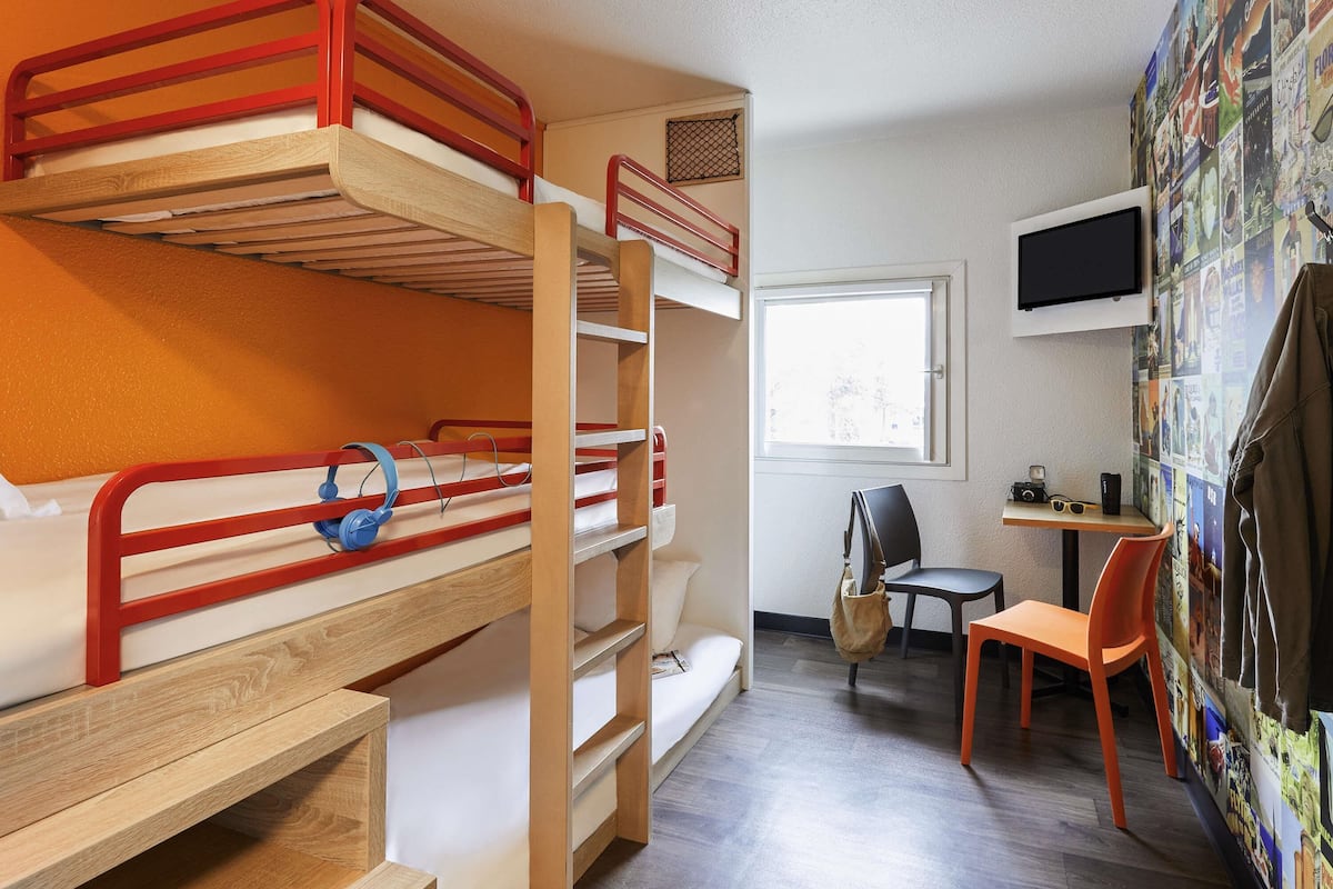 A bunk bed room with a desk, chair, and a wall with pictures.