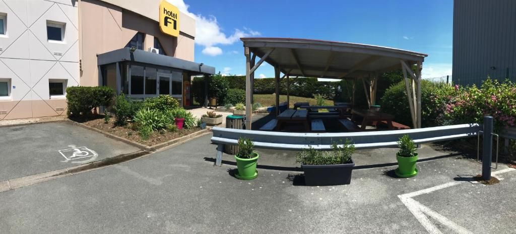 Entrada d'hotel amb una zona d'estar exterior coberta, un aparcament reservat per a persones amb mobilitat reduïda i un edifici amb un senyal groc.