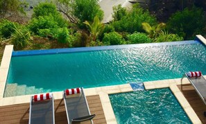 A swimming pool with a wooden deck and lounge chairs. - The Marion Villa (Scarborough)