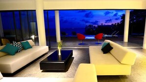 A modern living room with a sofa, a coffee table, and two red chairs. - The Marion Villa (Scarborough)