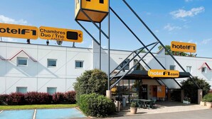 A hotel with a prominent 'hotelF1' sign, a swimming pool, and outdoor seating area. - hotelF1 Rungis Orly (Rungis)