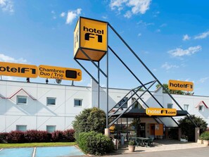 A hotel with a prominent 'hotelF1' sign, a swimming pool, and outdoor seating area.