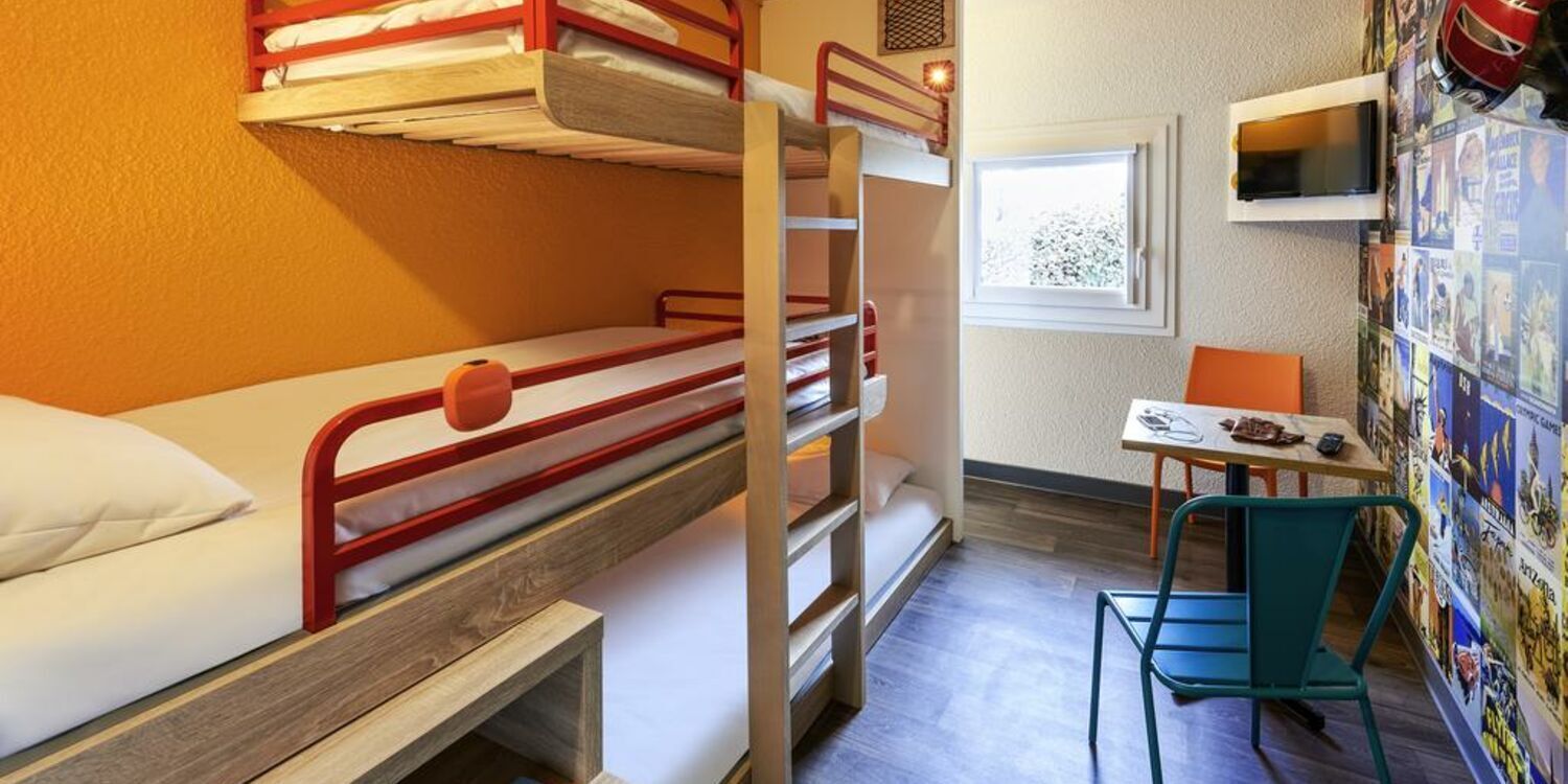 Une chambre avec un lit superposé, un bureau et une chaise, une fenêtre et un mur décoré de posters.