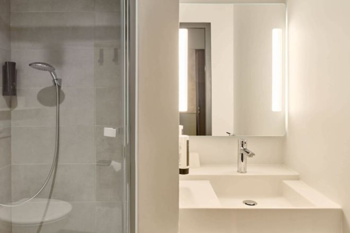 Ein modernes Badezimmer mit einer Duschkabine, einem Waschbecken mit Spiegel und einer Toilette.