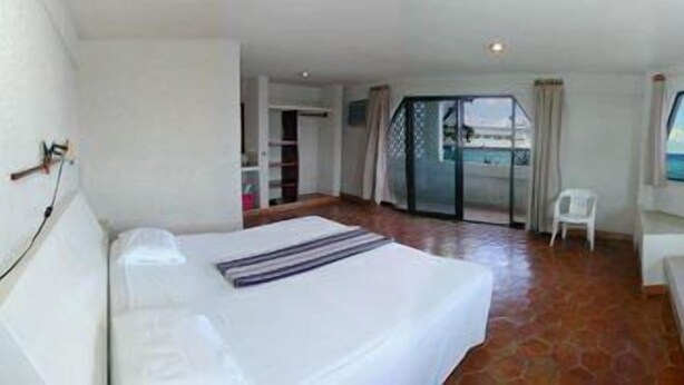 A hotel room with a bed, a sofa, and a large window offering a view of the sea. - Safari Inn (Cozumel)