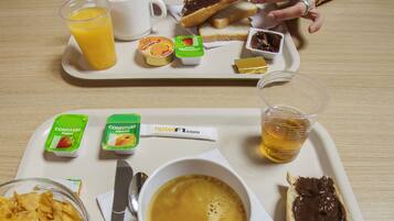 Una bandeja de desayuno con una taza de café, crema de chocolate en tostada, un vaso de jugo de naranja y un tazón de cereal.