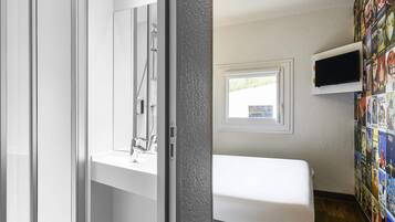 Ein modernes Badezimmer mit Dusche, Toilette und Waschbecken. Ein Fenster bietet Blick ins Freie.