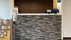 A reception area with a stone wall, a counter, and a digital kiosk.