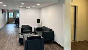 A hotel lobby with a seating area, a reception desk, and a door leading to another room.