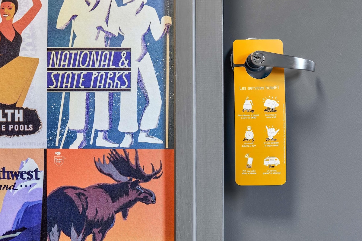 Une porte sur laquelle est apposée une pancarte jaune indiquant les services offerts par l’hôtel, tels que le Wi-Fi, le parking et un service en chambre disponible 24 heures sur 24, 7 jours sur 7.