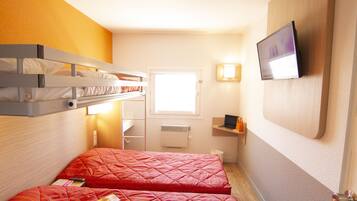 A compact hotel room with bunk beds, a television, a small desk, and a window.