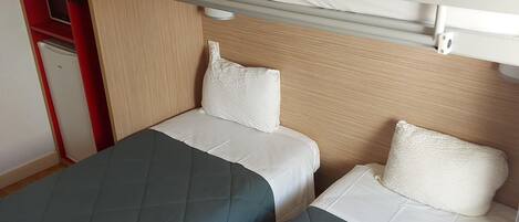 A bunk bed room with two beds, a small desk, and a refrigerator.