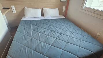 A bed with a quilted blue cover, white pillows, and a wooden headboard.