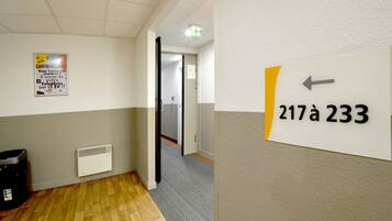 A hallway with a sign indicating room number 217a 233, a poster on the wall, and a radiator.