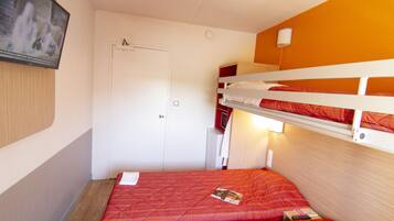 A room with two bunk beds, a television mounted on the wall, a door, and a small table with a remote control.