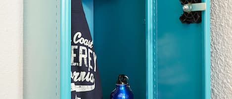 A teal door with a towel hanging on the inside handle and a blue water bottle placed on the floor.