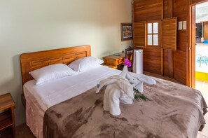 A wooden-framed bed with white linens, a small bedside table, and a decorative towel on the bed.