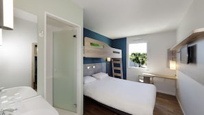 Een moderne hotelkamer met een bed, een badkamer met een wastafel en spiegel, een raam met uitzicht en een televisie aan de muur.