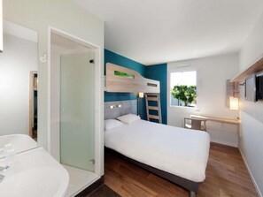 A modern hotel room with a bed, a bathroom with a bathtub, a desk, and a window with a view. - ibis budget Paris Porte d'Orleans (Paris)