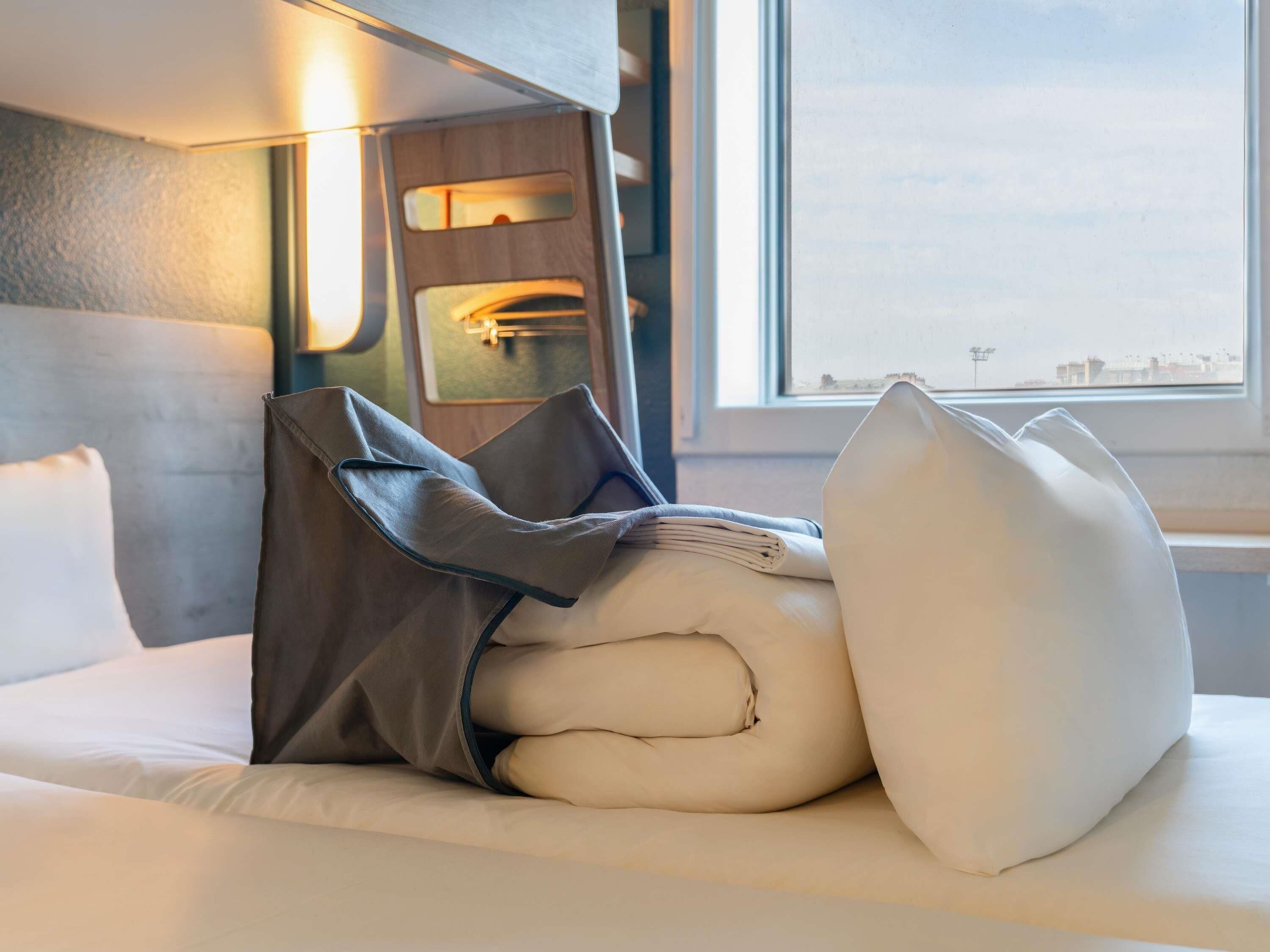 Habitación de hotel con cama, almohadas, cabecero y ventana con vistas.