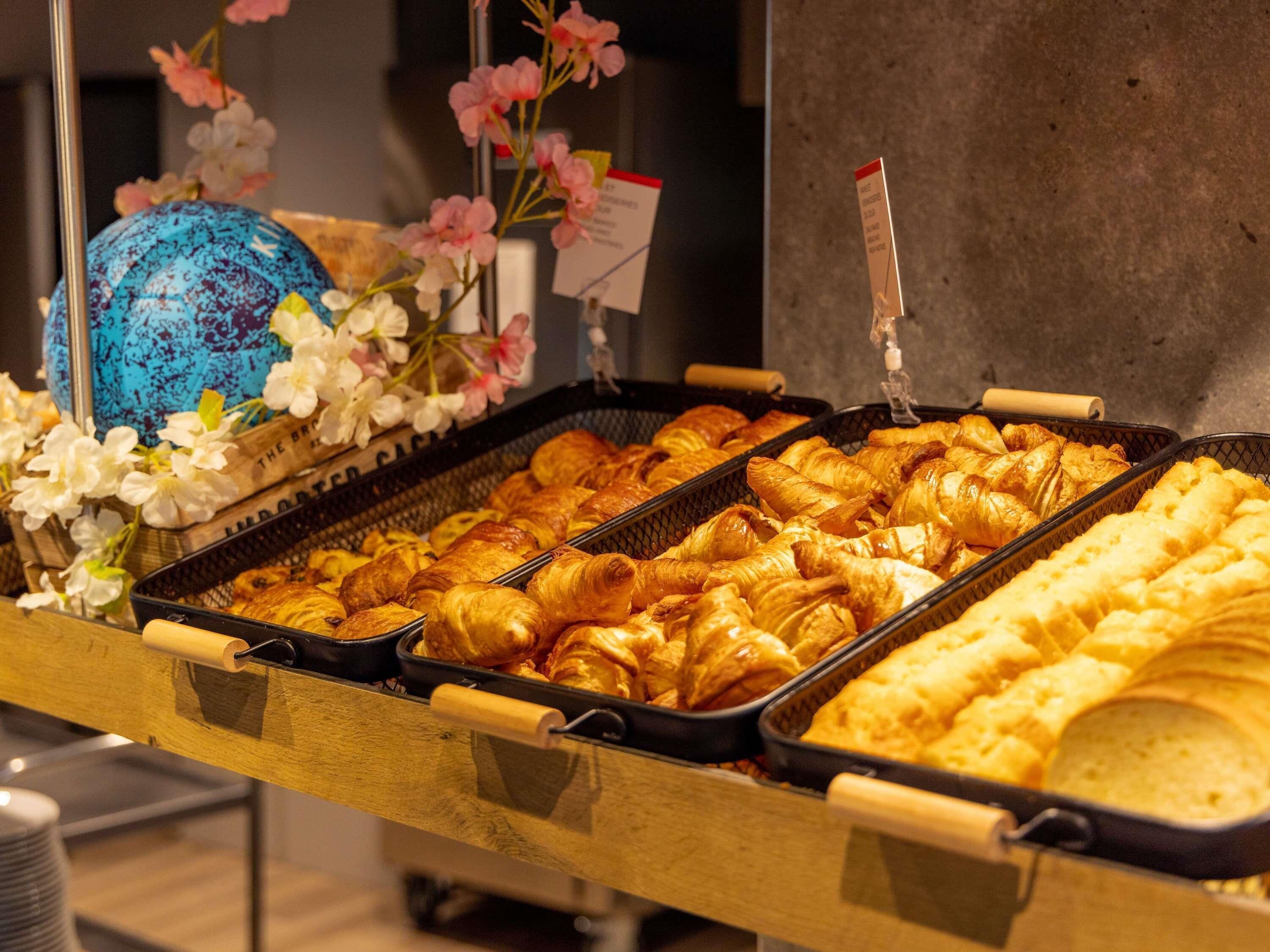 Un buffet proposant une variété de produits de boulangerie, notamment des croissants et des petits pains, présentés sur des plateaux.
