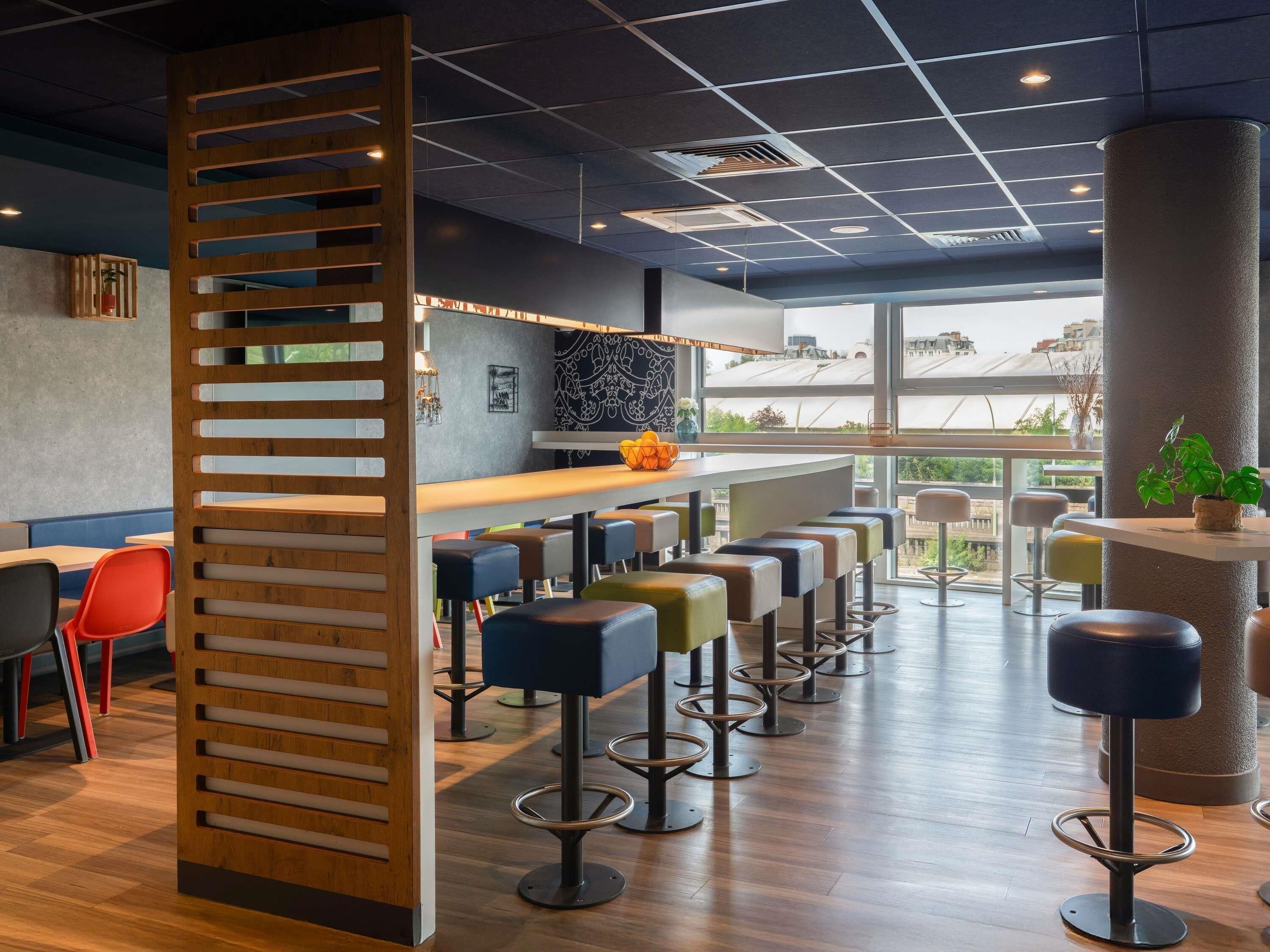 A modern bar area with high stools and a wooden partition.
