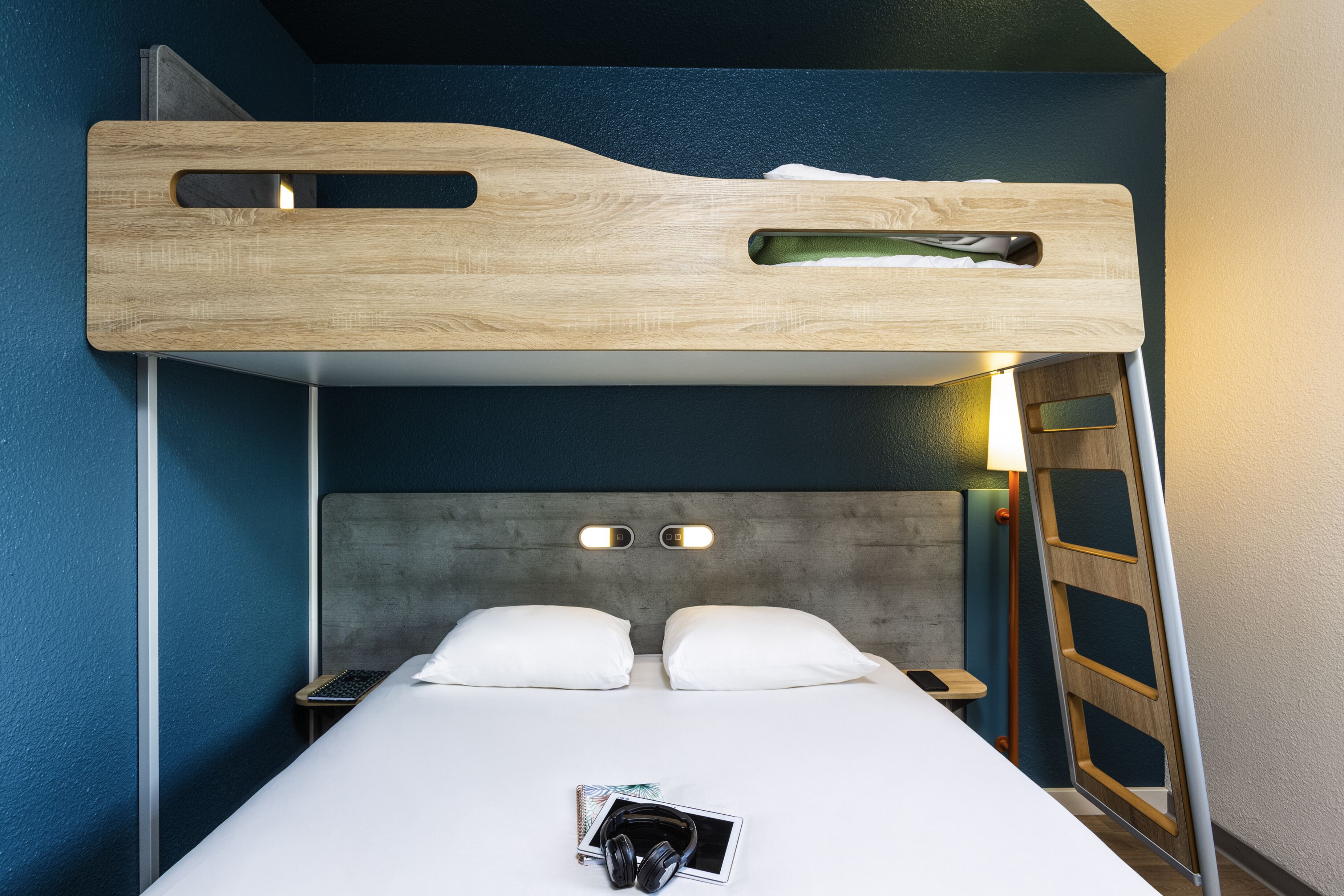 Una cama litera con cabecera de madera, dos mesitas de noche y una escalera.
