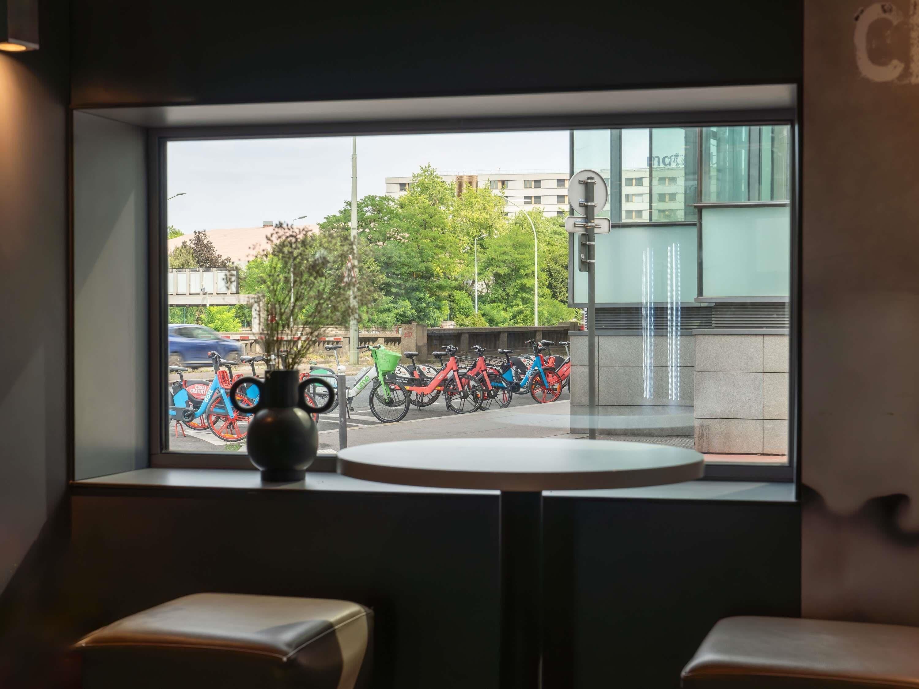 A view from inside a room with a window overlooking a parking area with bicycles.