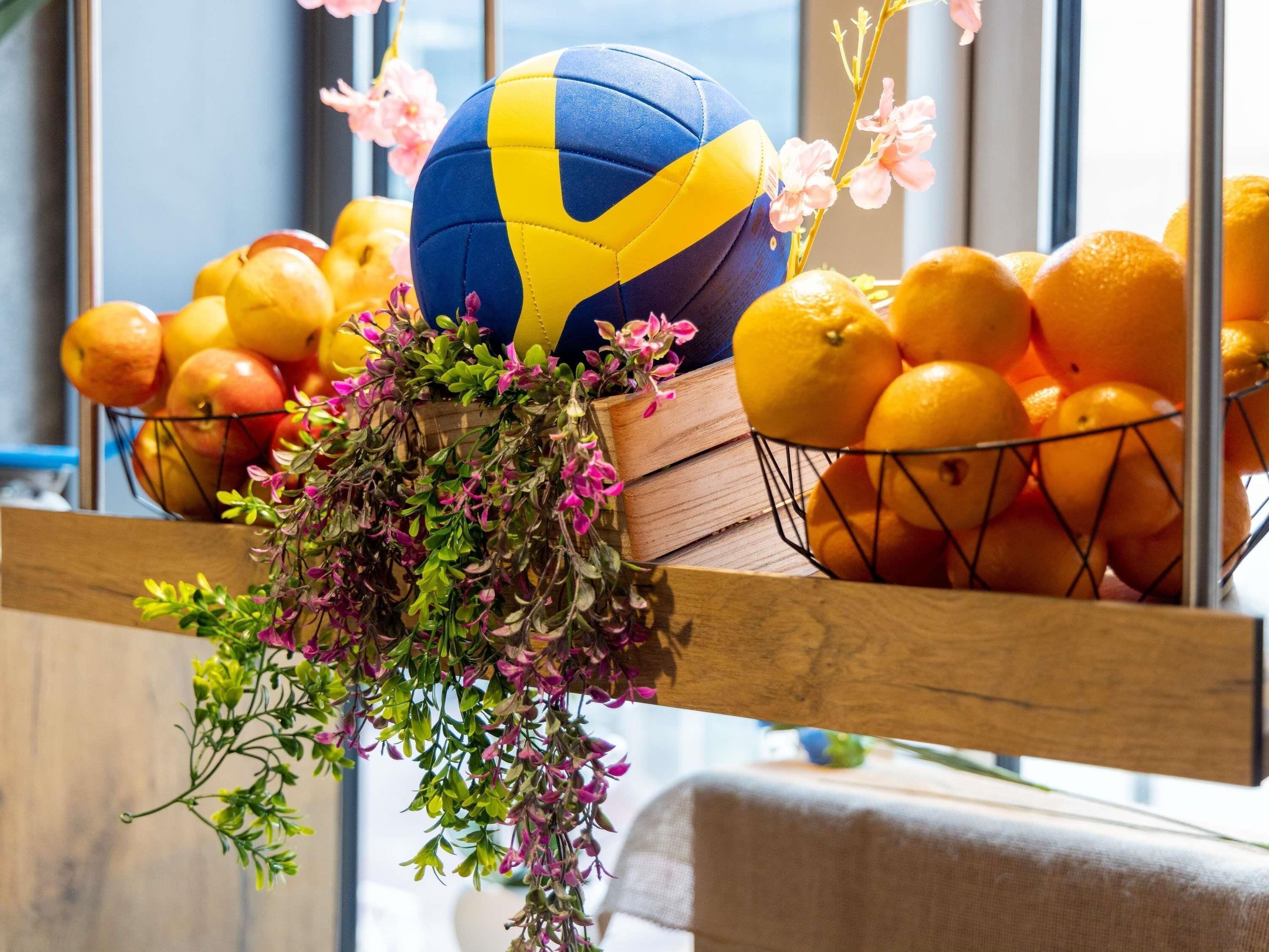 A volleyball, oranges, and a basket of flowers.