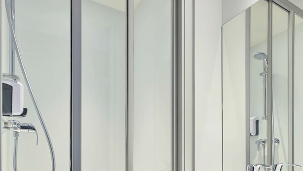 A modern bathroom with a glass shower enclosure, a handheld showerhead, and a wall-mounted faucet. - hotelF1 Clermont-Ferrand East (Clermont-Ferrand)