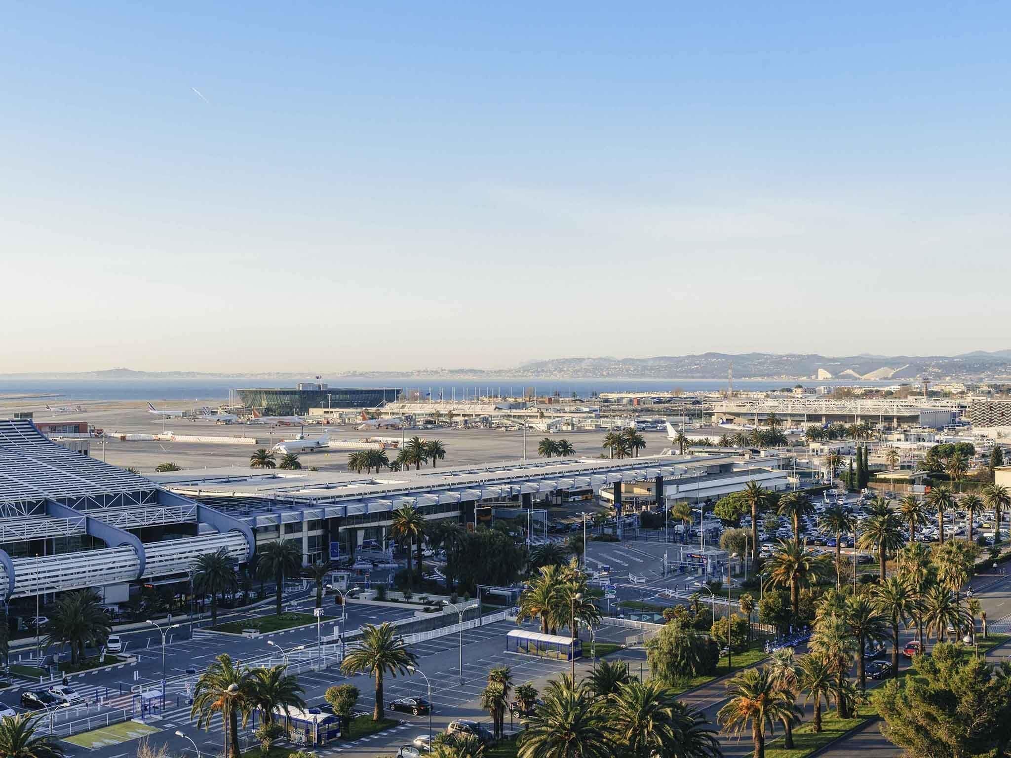 An airport terminal with a modern design, including a curved roof structure and a large open space for passengers.